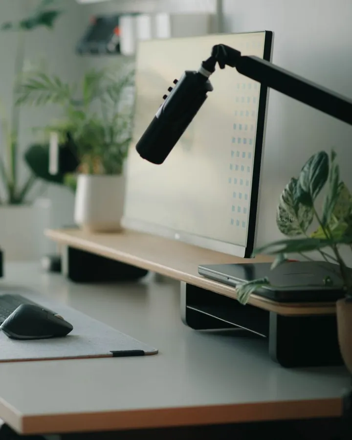 Un poste de travail : écran posé sur un rehausseur, clavier et souris devant
